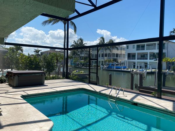 A beautiful view of a pool enclosure right next to a lake in Naples, Florida.